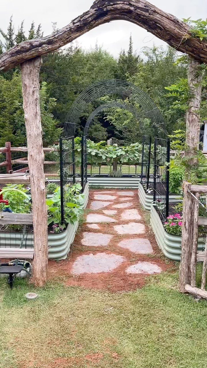 Above Ground Garden Ideas: 12 Ways to Build a Raised Bed 3 Corrugated metal raised garden beds line a stone path leading through a black metal garden archway.