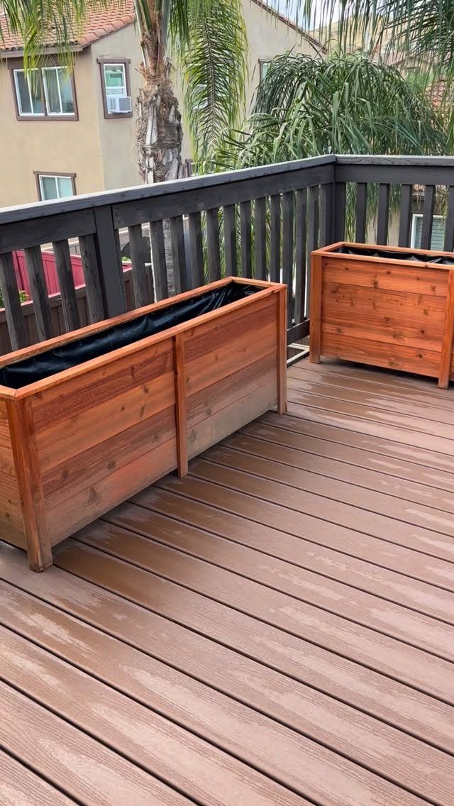 17 Backyard Deck Designs for Every Yard and Budget 11 Two wooden planter boxes sitting on a brown composite deck with a dark railing.
