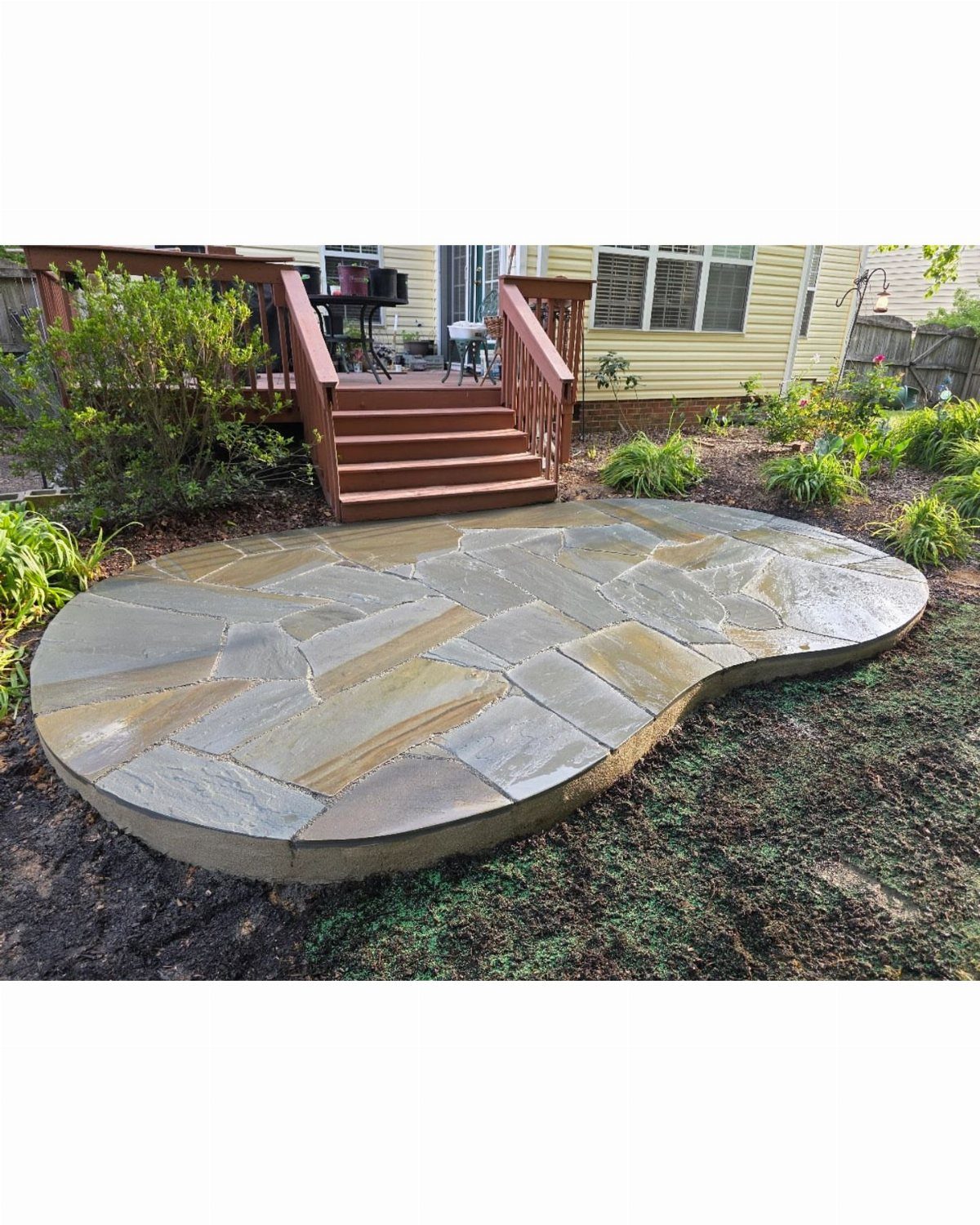 A curved flagstone patio made of natural stone pieces set in a garden landscape.