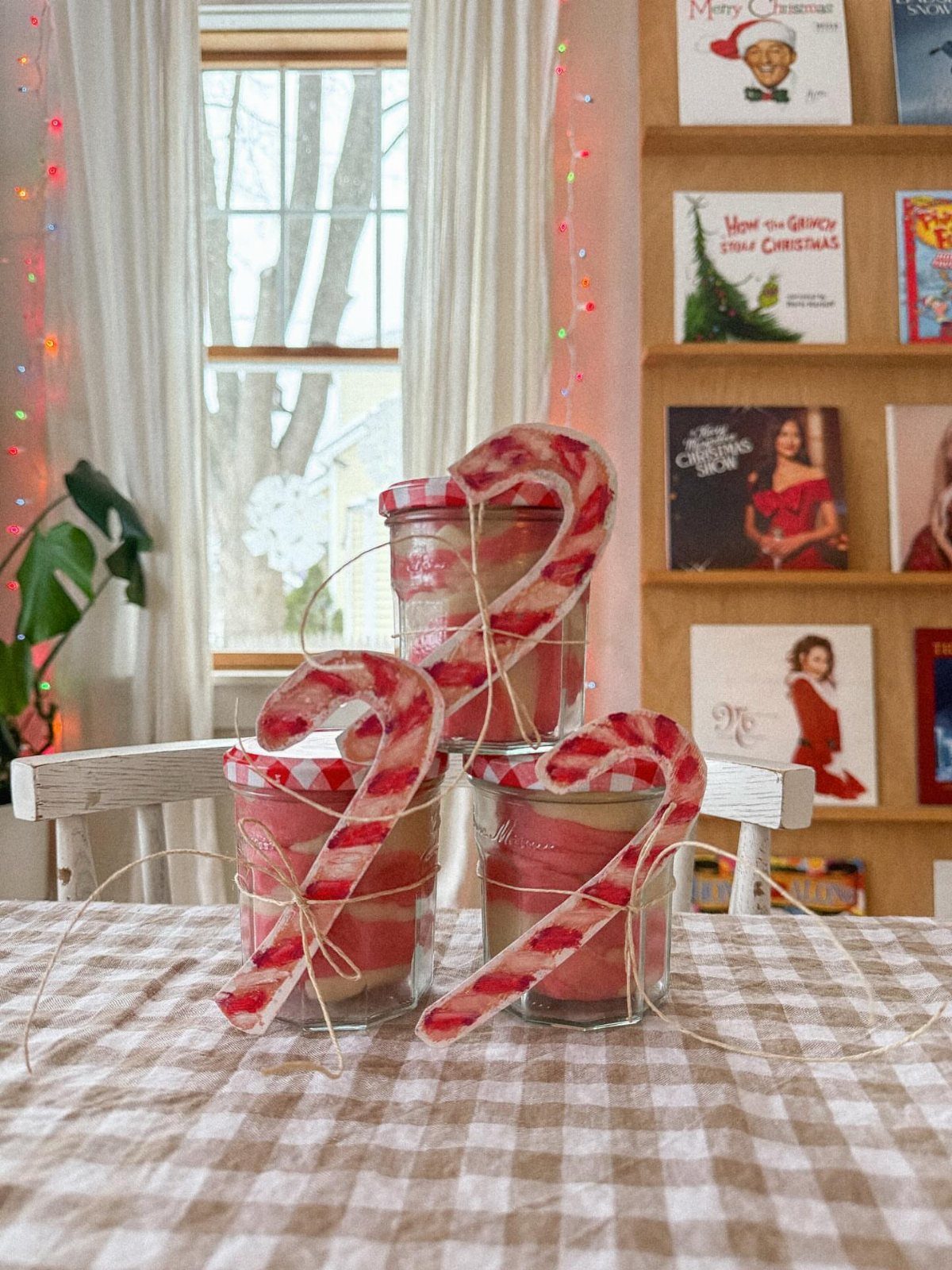 Three glass jars filled with red and white striped playdough decorated with candy canes.