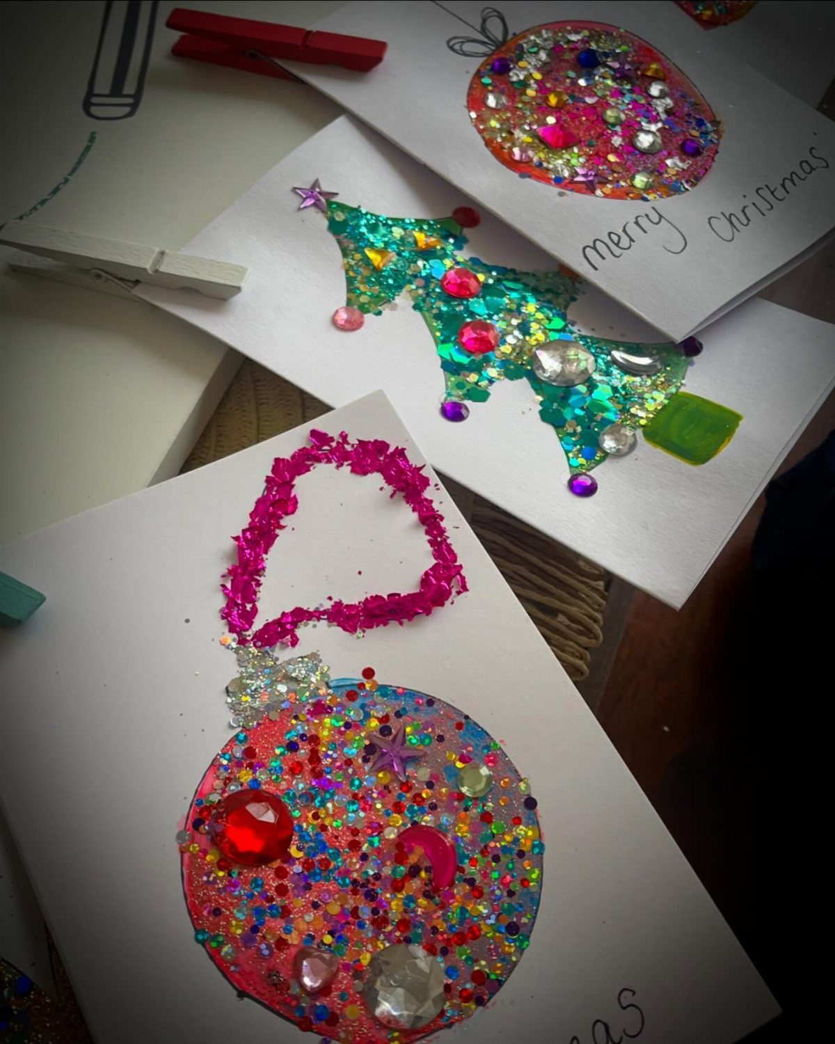 Handmade Christmas cards decorated with colorful glitter ornaments and a sparkling Christmas tree.