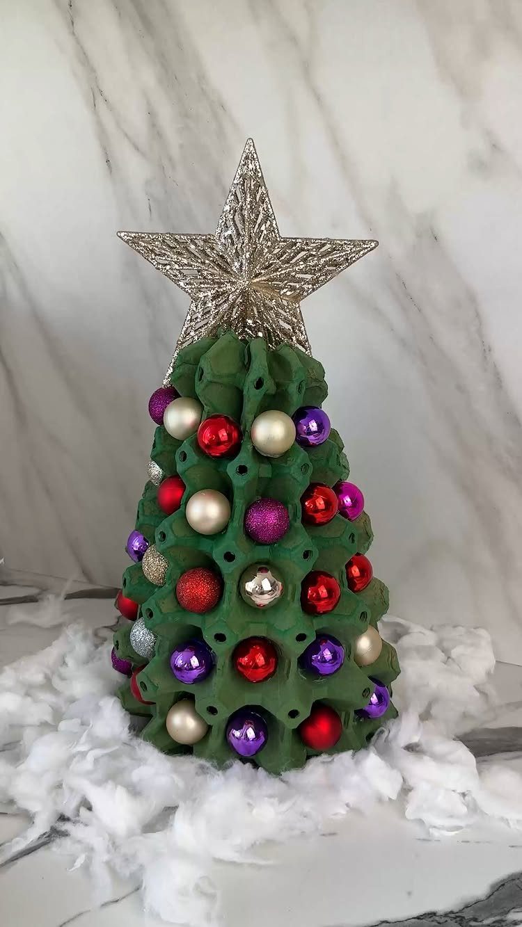 A green egg carton Christmas tree decorated with colorful ornaments and a silver star.
