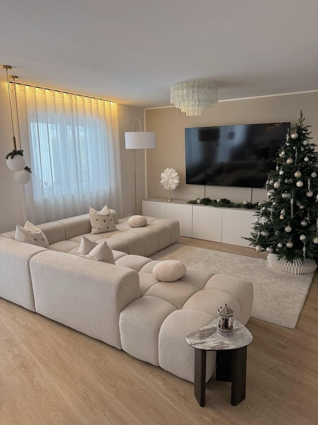 A bright modern living room featuring a white sectional sofa and a decorated Christmas tree.