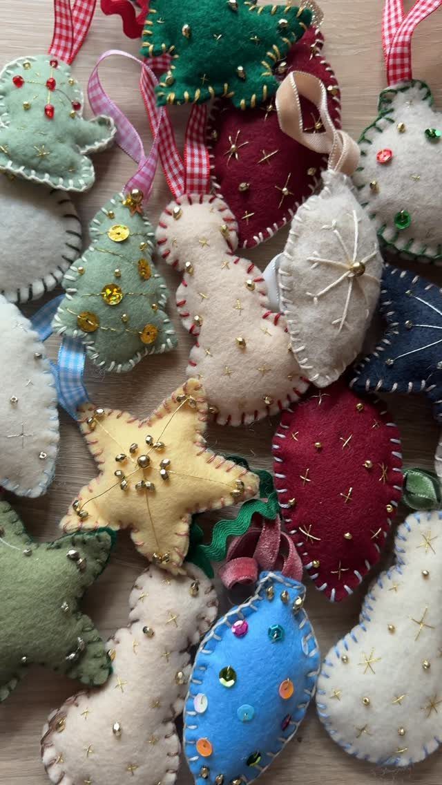 Handmade felt Christmas ornaments in various shapes and colors scattered on a light wooden surface.