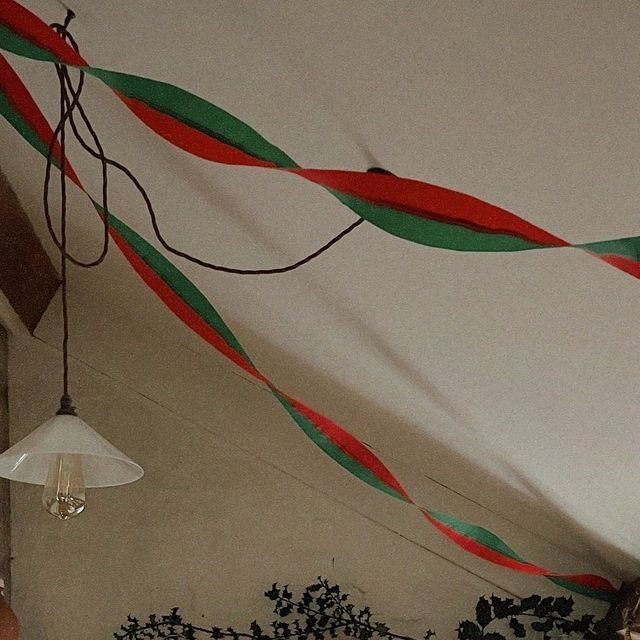 Red and green crepe paper streamers draped across a white ceiling near a hanging lamp.
