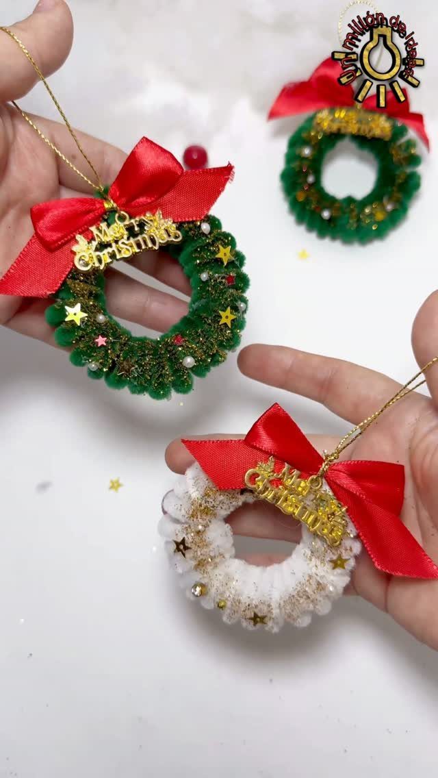 Hands holding three small handmade Christmas wreath ornaments with red bows and gold lettering.