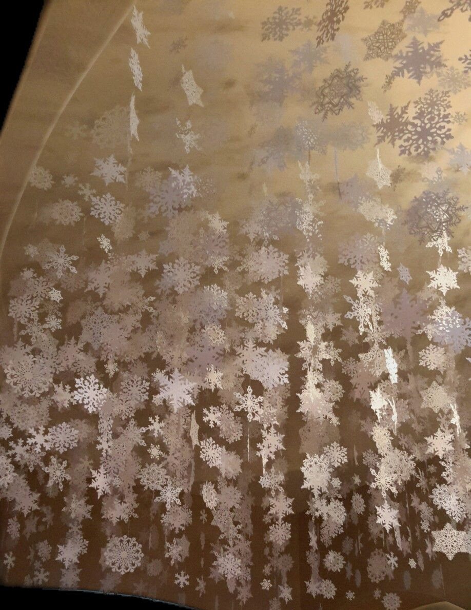 White paper snowflakes hanging in dense layers from a ceiling to create a winter effect.