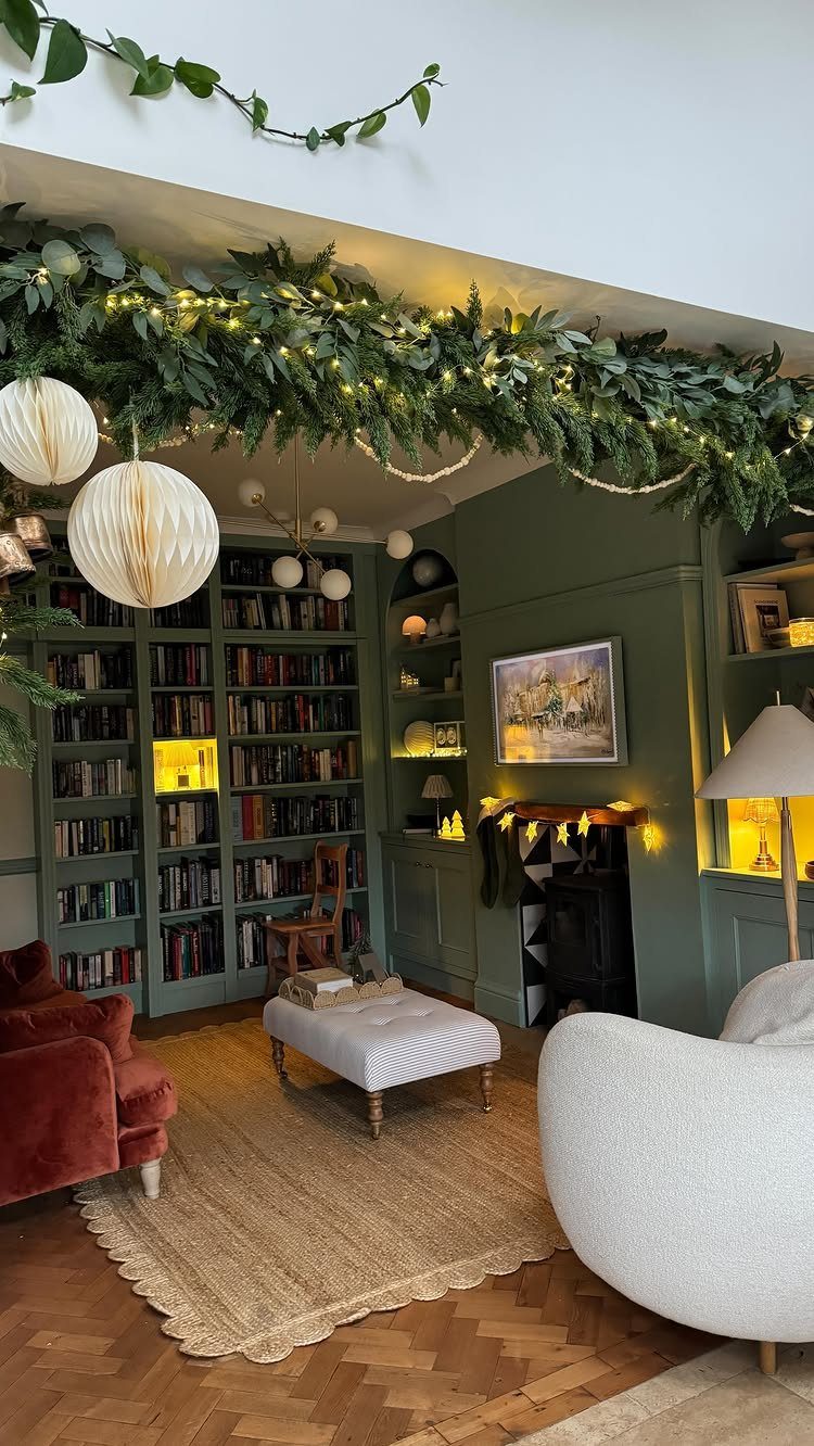 Green pine garland with warm fairy lights draped across a white ceiling beam in a living room.