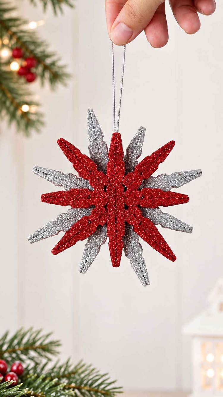 A hand holding a glittery red and silver star ornament made from clothespins.