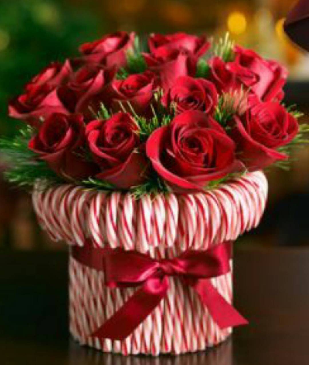 Red roses arranged in a container made of red and white striped candy canes.