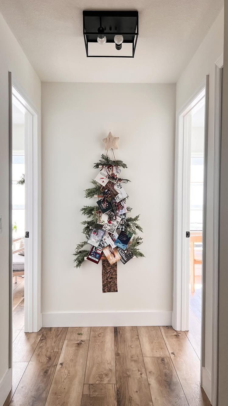 Evergreen branches shaped like a Christmas tree on a wall, decorated with hanging holiday cards.