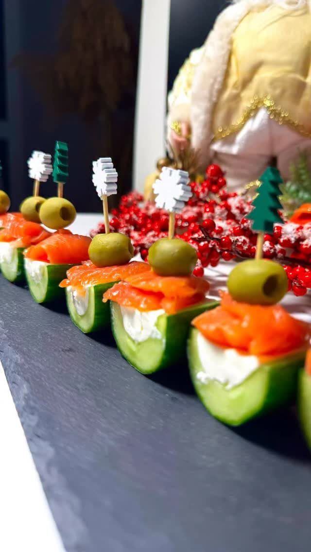 Cucumber slices topped with cream cheese, smoked salmon, and olives on a slate platter.