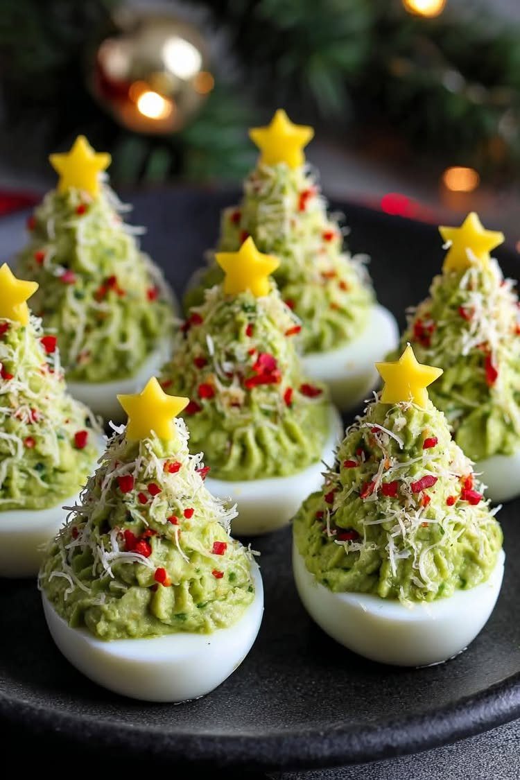 Green avocado deviled eggs decorated to look like small Christmas trees with yellow stars.