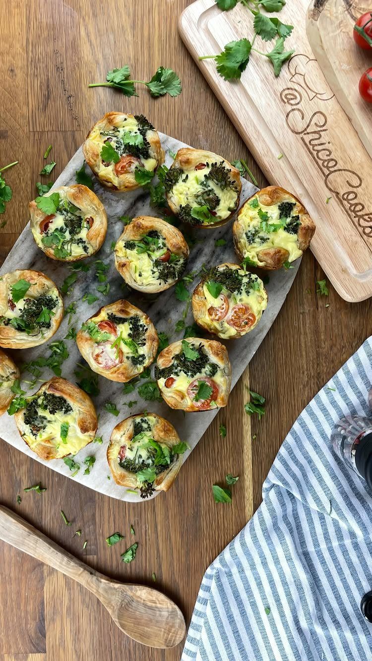 Small savory pastry tarts with green vegetable filling arranged on a marble serving platter.