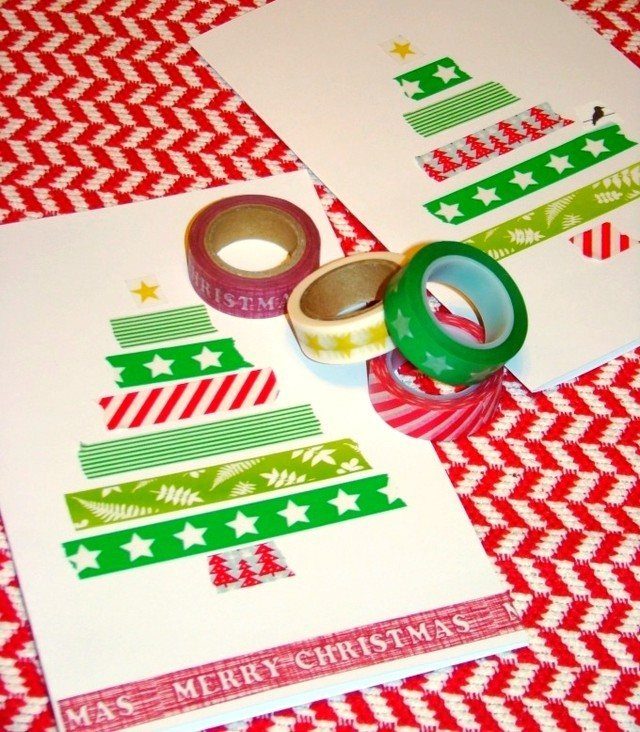 8 Christmas Tree Wall Ideas: String Lights to Pallet Builds 4 Washi tape rolls next to white cards decorated with Christmas trees made of patterned tape strips.