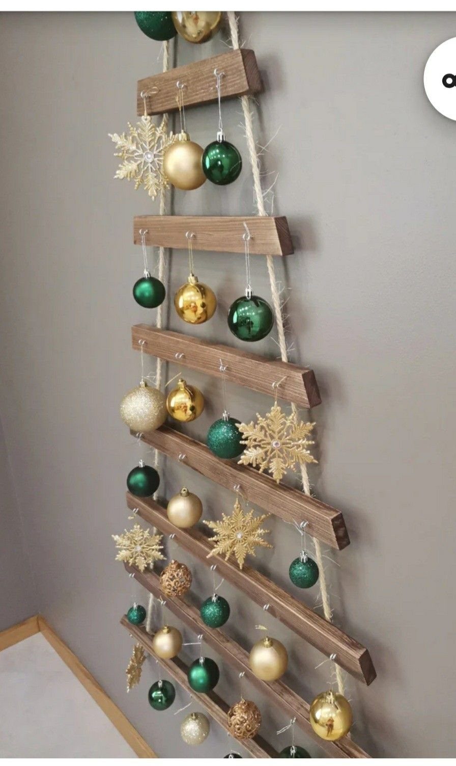 8 Christmas Tree Wall Ideas: String Lights to Pallet Builds 7 Wooden slats arranged in a triangle on a wall, decorated with gold and green ornaments.