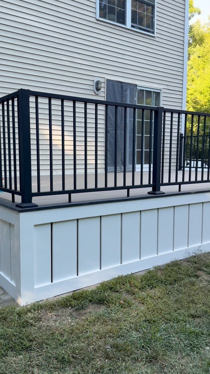 Composite Deck Skirting: 5 Ideas That Close the Gap 5 White vertical board and batten skirting installed around the base of a wooden deck with black railings.