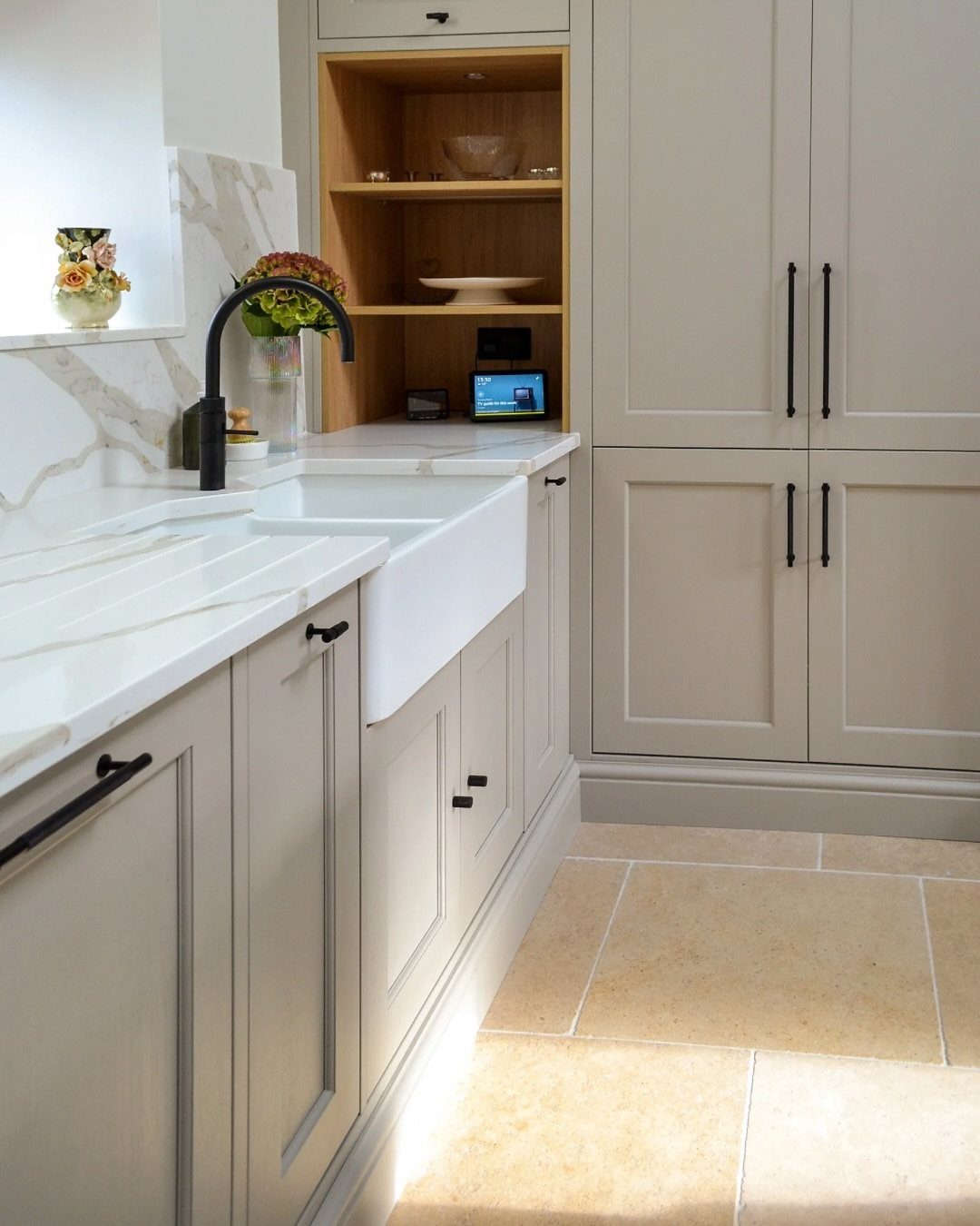 Light grey shaker-style kitchen cabinets with black handles and a white marble countertop.