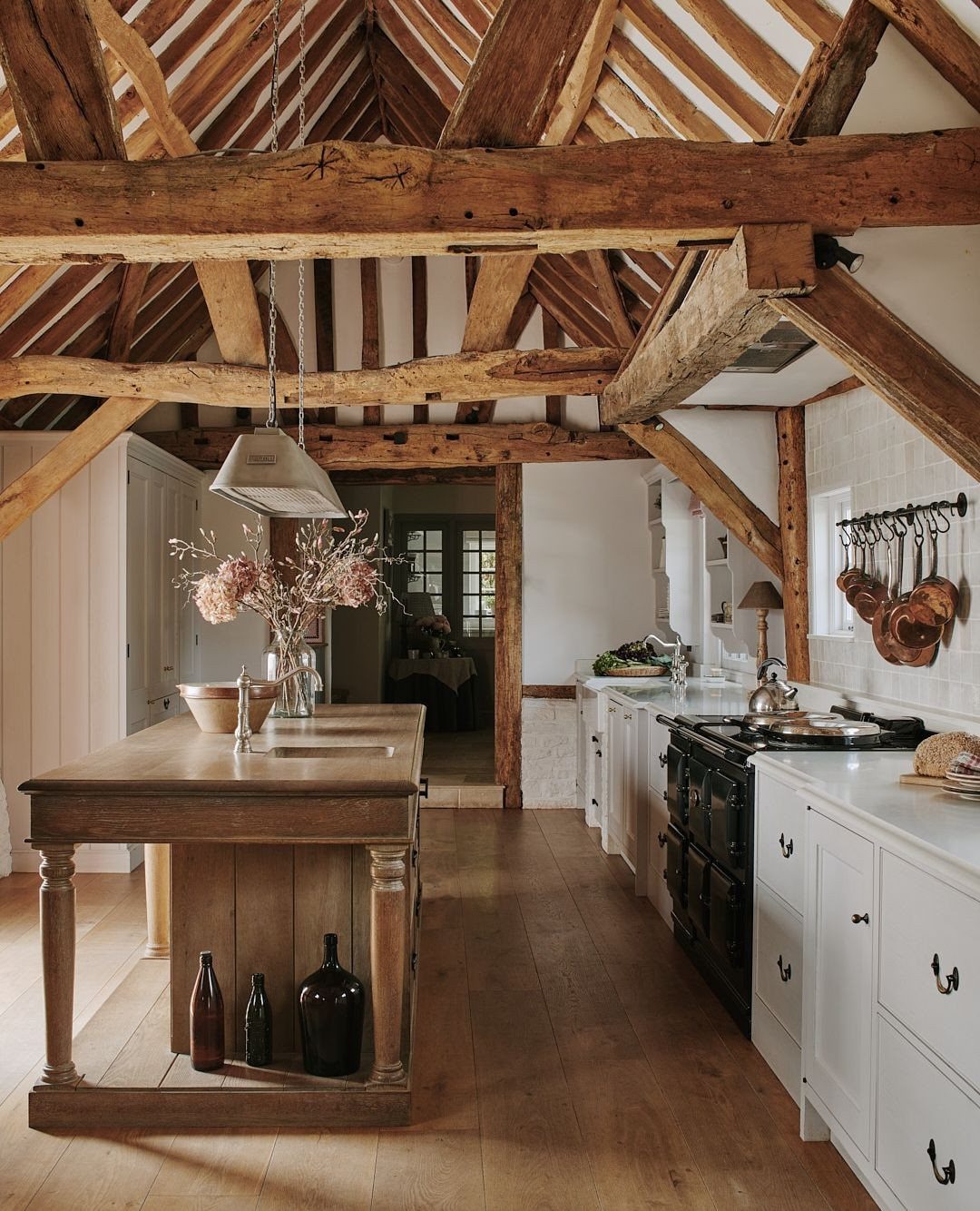 Rustic kitchen with large exposed wooden ceiling beams and a central wooden island.