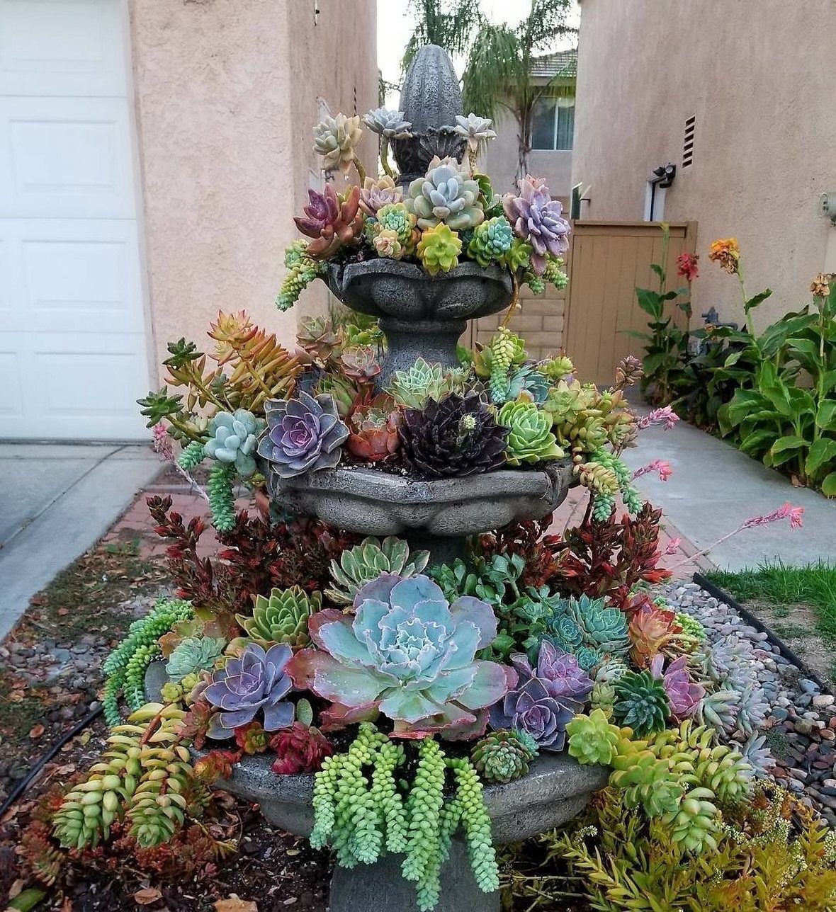 25 Creative and Gardening Ideas for Backyards Big or Small 19 A tiered stone fountain filled with a lush variety of colorful succulents in a garden.