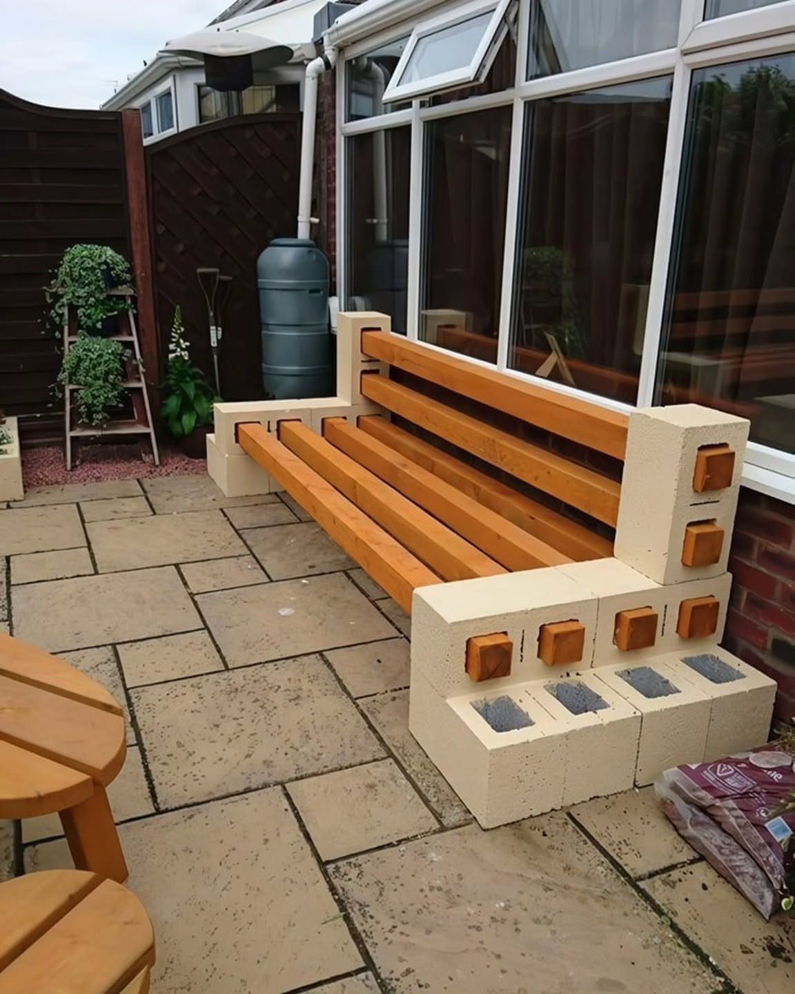 9 Deck Bench Seating Ideas for Storage, Planters and Rail-Top Perches 5 A DIY outdoor bench made of concrete blocks and wooden slats on a stone patio.