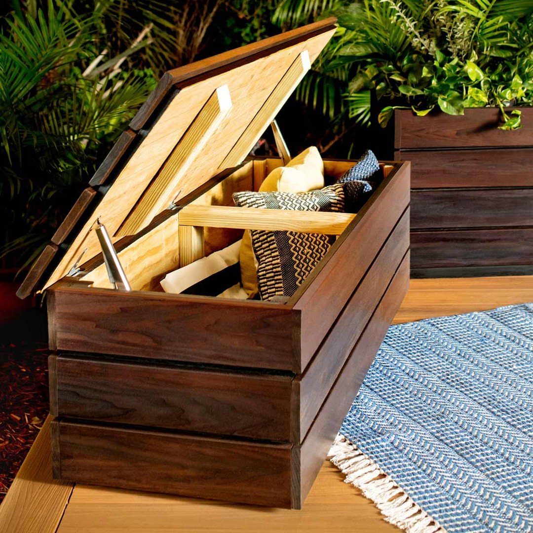 9 Deck Bench Seating Ideas for Storage, Planters and Rail-Top Perches 1 An open dark wood storage bench filled with decorative pillows on a wooden deck.