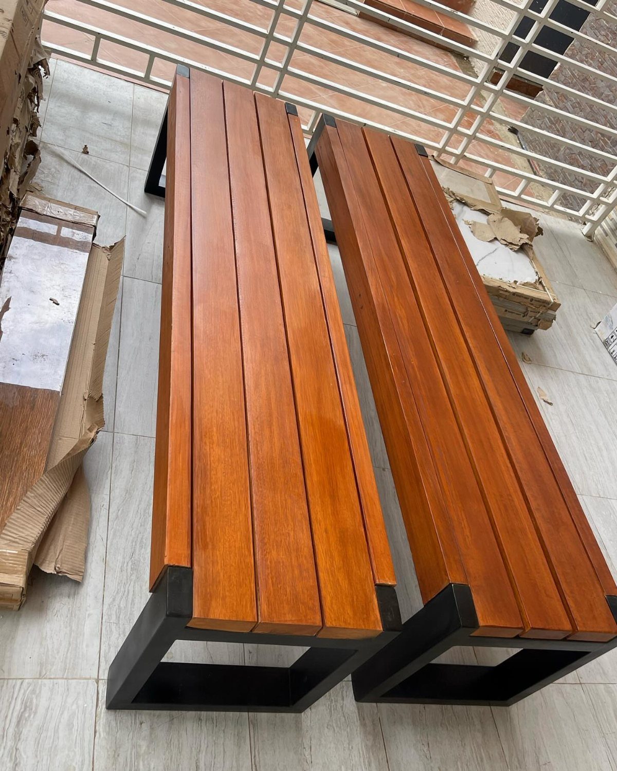 9 Deck Bench Seating Ideas for Storage, Planters and Rail-Top Perches 9 Two wooden slat benches with black metal frames resting on a tiled floor.