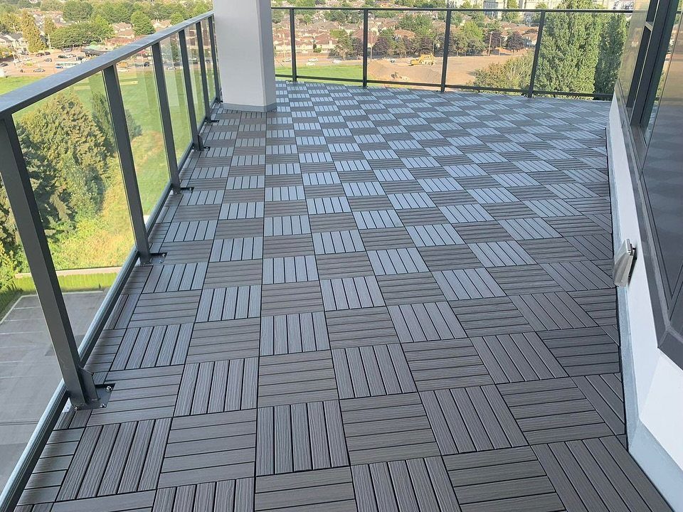 12 Deck Floor Design Ideas for Picture-Frame Borders to Patterned Layouts 12 Grey interlocking deck tiles arranged in a checkered pattern on a modern balcony with glass railings.