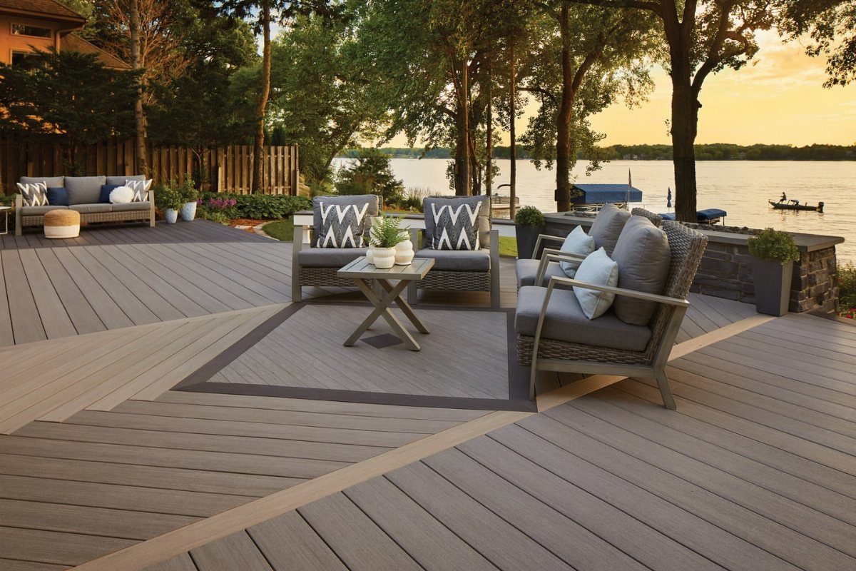 12 Deck Floor Design Ideas for Picture-Frame Borders to Patterned Layouts 6 A multi-toned grey and tan composite deck with outdoor lounge furniture overlooking a lake at sunset.