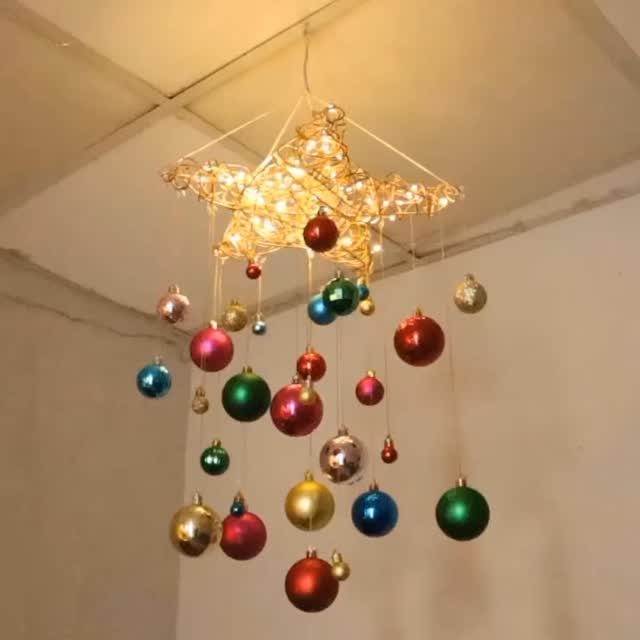11 DIY Christmas Holiday Decorations: From Wine Corks to Walnut Reindeer 4 A glowing wire star ornament hanging from a ceiling with colorful baubles suspended below it.