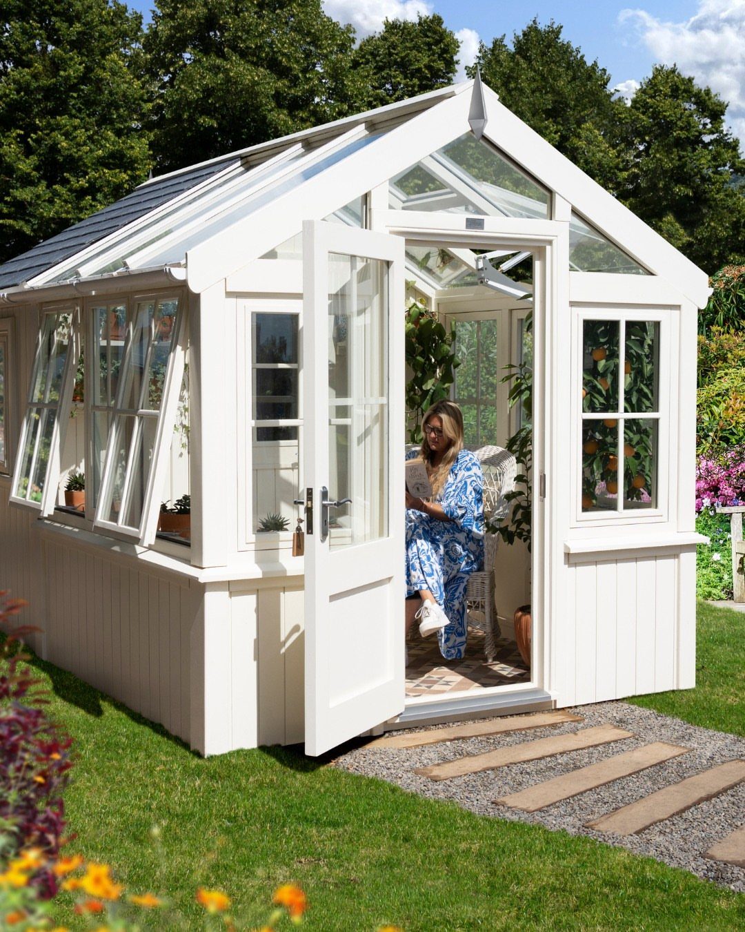 10 Ideas for Farmhouse Shed Home Style 2 A white wooden greenhouse potting shed with glass windows sitting on a green lawn.