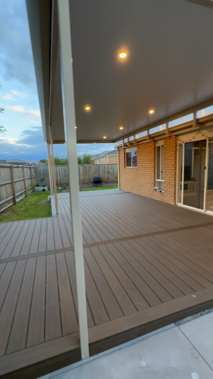 A large wooden deck extends from a brick house under a covered patio area.