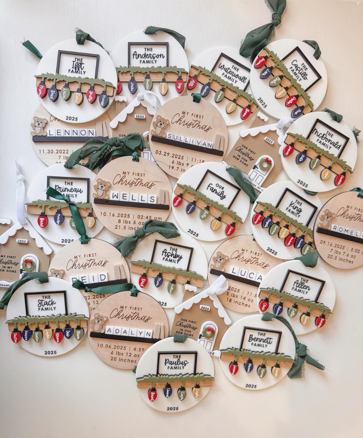 Numerous personalized wooden baby's first Christmas ornaments with names and birth details scattered on white.