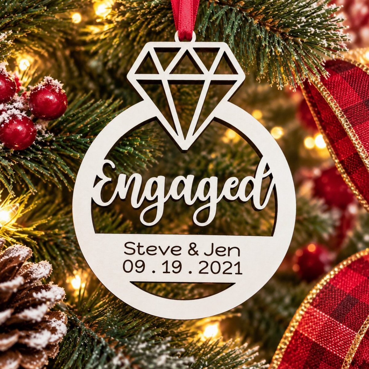 A wooden engagement ornament shaped like a ring hanging on a decorated Christmas tree.