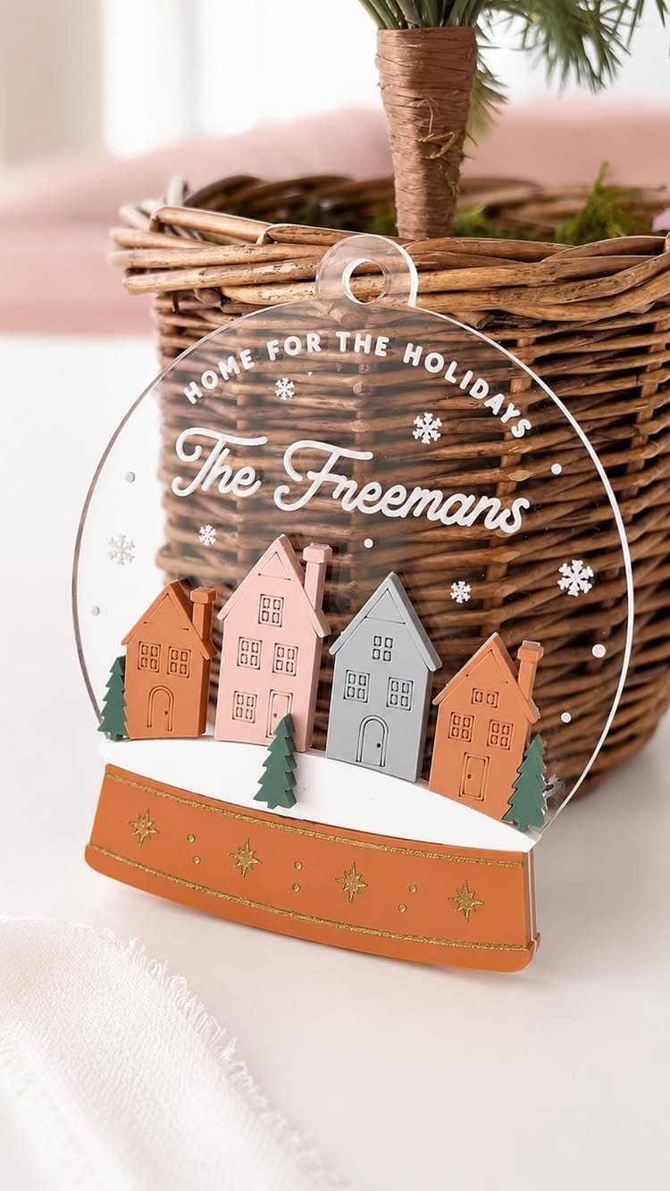A clear acrylic Christmas ornament with colorful houses and the name The Freemans printed on it.