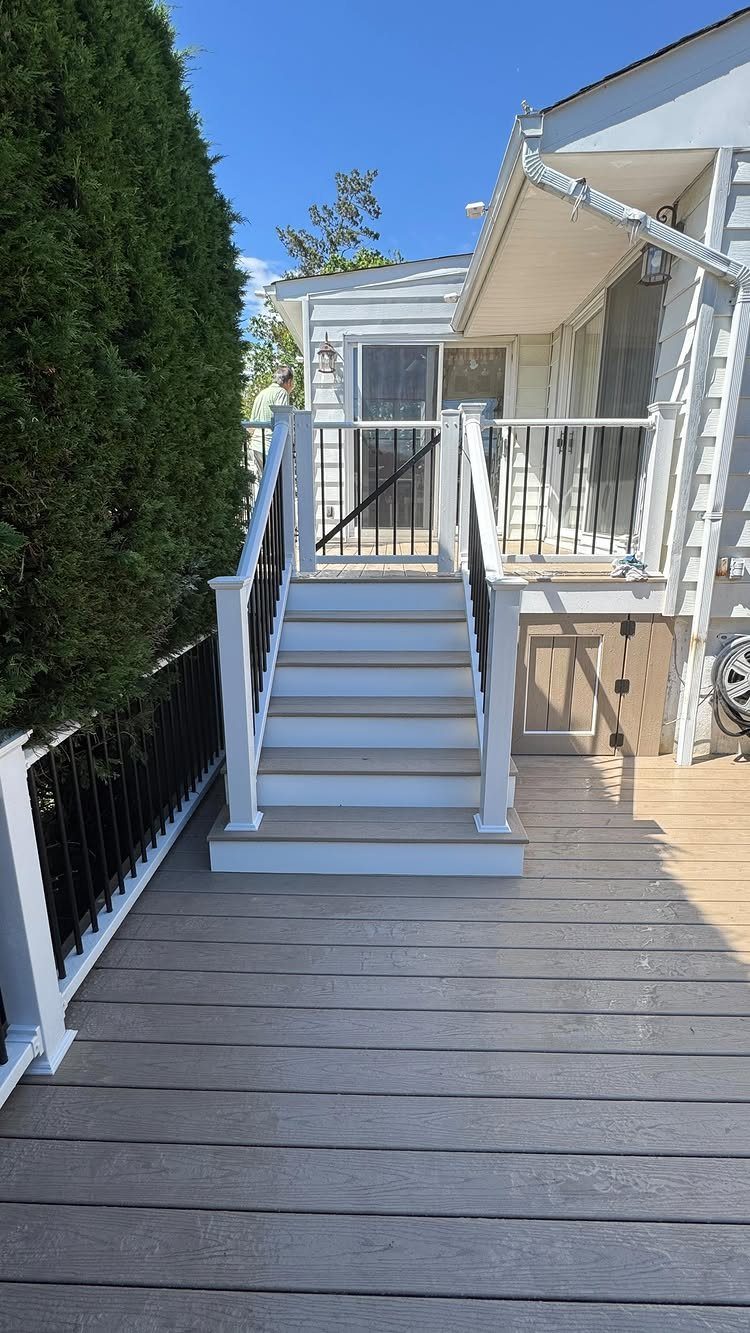 12 Porch and Deck Ideas for Outdoor Living 3 Light grey wooden deck with white railings and stairs leading to an elevated level.