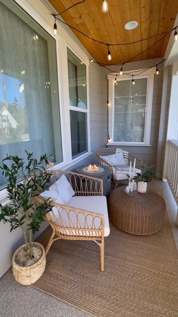 12 Porch and Deck Ideas for Outdoor Living 1 Two wicker armchairs and a woven ottoman sit on a small porch with string lights.