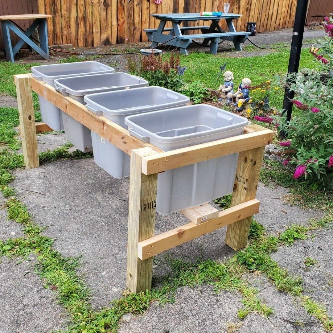 9 Raised Garden Ideas DIY Crafters Build from Scrap and Stone 6 Grey plastic storage bins held within a handmade wooden frame stand on a concrete patio.