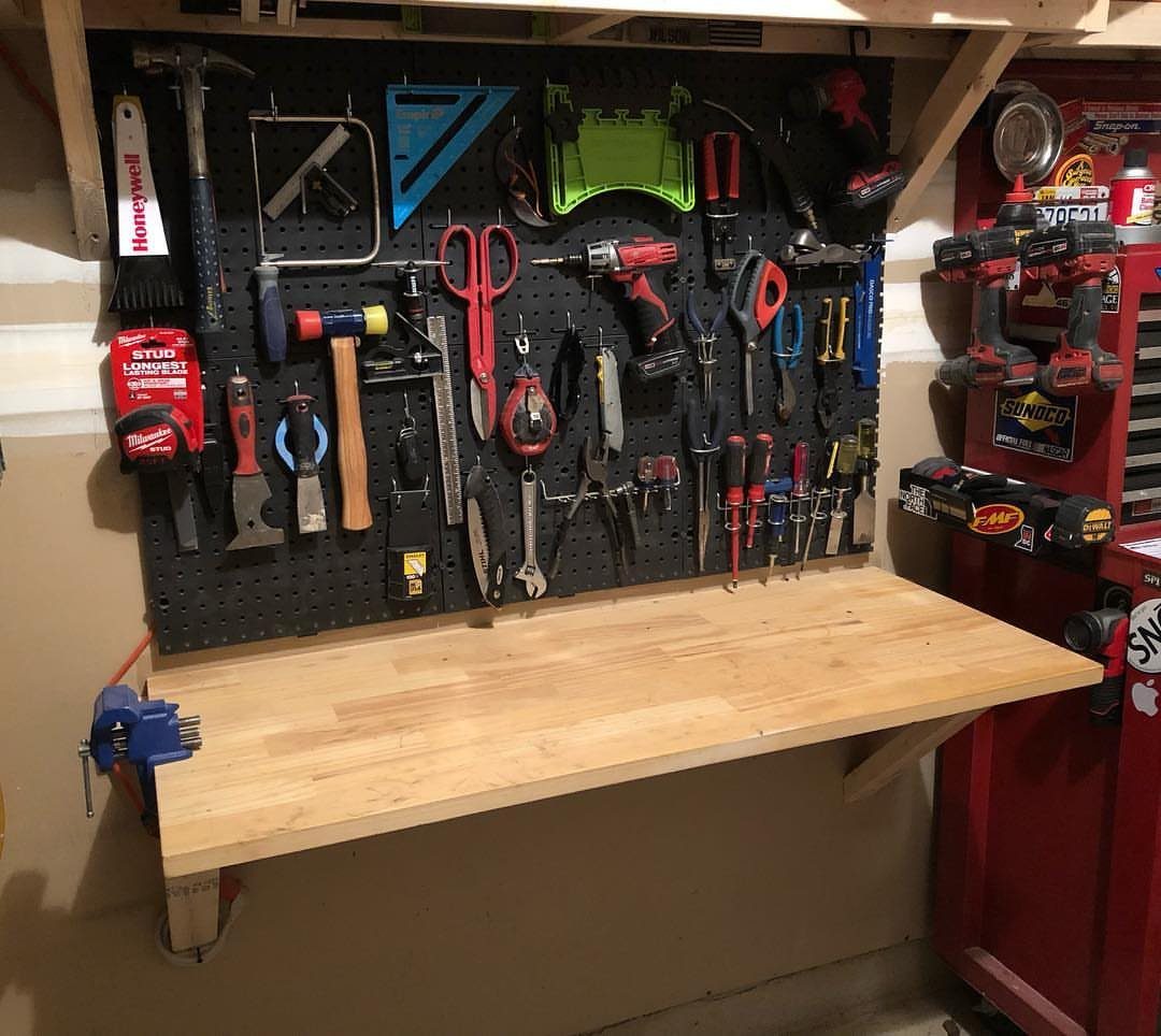 6 Small Garage Building Ideas for Storage, Projects & Living Space 3 A wooden fold-down workbench mounted below a pegboard filled with various garage tools.
