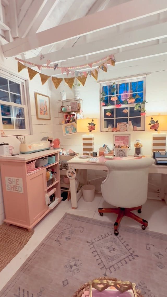 A pink decorated craft room with a white desk, office chair, and various supplies.