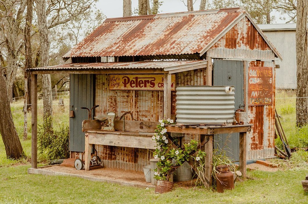 A rustic corrugated metal shed with a rusted roof and a wooden workbench outdoors.